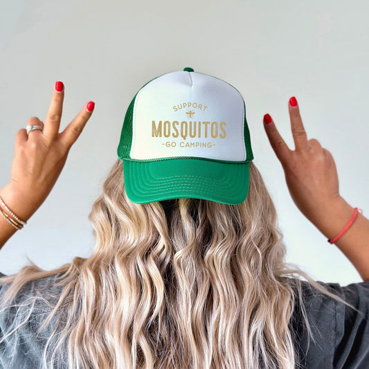 a woman with long blonde hair wearing a green and white trucker hat